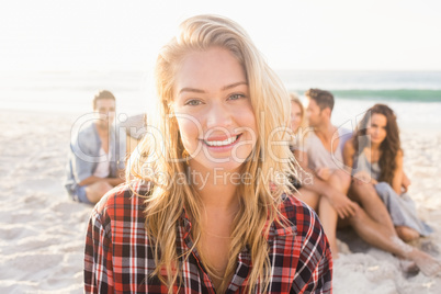 Smiling friends sitting on sand