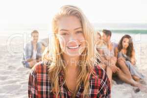 Smiling friends sitting on sand