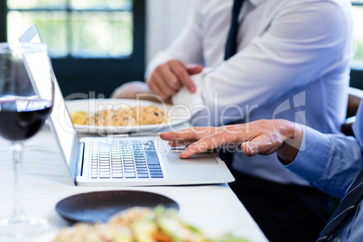 Close-up of man using laptop during a business lunch meeting