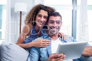 Portrait of young couple using a digital tablet on sofa