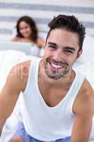 Man smiling while wife sitting on bed in background