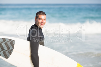 Portrait of happy man holding a surfboard on the beach