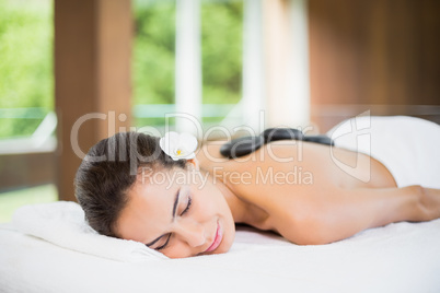 Young woman lying with spa stones at her back