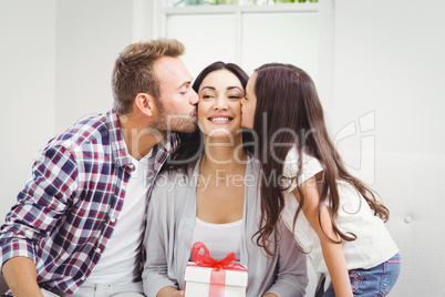 Man and daughter kissing woman holding gift
