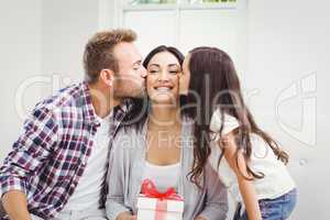 Man and daughter kissing woman holding gift