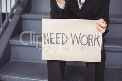 Midsection of unemployed businesswoman with need work placard