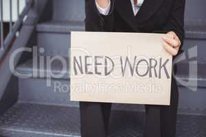 Midsection of unemployed businesswoman with need work placard