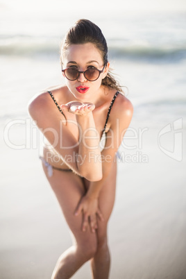 Glamorous woman blowing a kiss on the beach