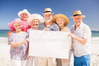 Smiling senior friends holding blank paper