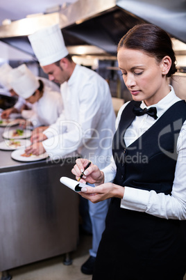 Waitress with note pad in commercial kitchen