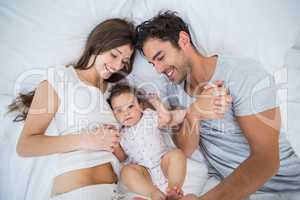 High angle view of family lying on bed and enjoying