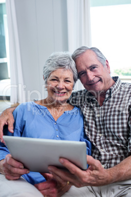 Portrait of senior couple using a digital tablet on sofa