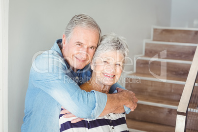 Portrait of cheerful senior couple embracing on staircase