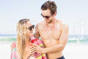 Young couple in sunglasses embracing on the beach