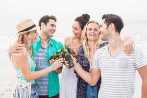 Group of friends toasting beer bottles on the beach