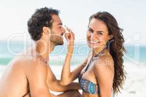 Happy girlfriend putting sunscreen on boyfriends nose