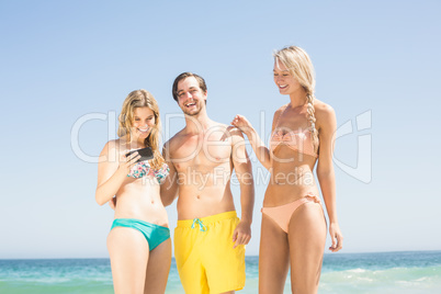 Young friends looking at mobile phone on the beach