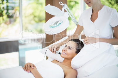 Smiling young woman receiving facial massage