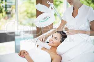 Smiling young woman receiving facial massage