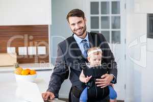 Businessman using laptop while carrying daughter