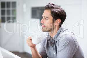 Thoughtful young man holding coffee cup