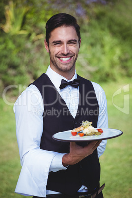 Handsome waiter holding a plate