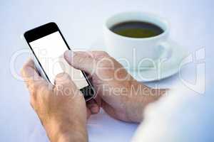 Casual businessman using smartphone and having coffee