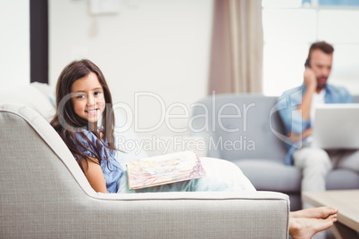 Girl with picture book while father in background