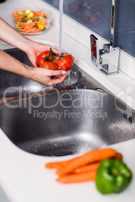 Woman washing tomatoes at kitchen washbasin