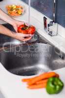 Woman washing tomatoes at kitchen washbasin