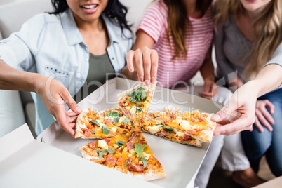 Midsection of young female friends eating pizza