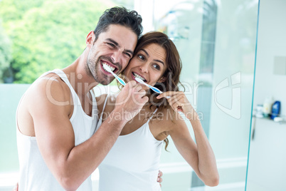 Young couple brushing teeth while standing in bathroom