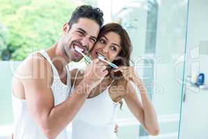 Young couple brushing teeth while standing in bathroom