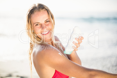 Portrait of happy woman applying sunscreen lotion on the beach
