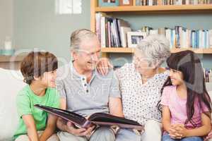 Grandparents showing album to grandchildren