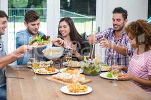 Multi-ethnic friends having meal at table in house