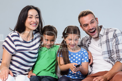 Happy family watching television with their two children