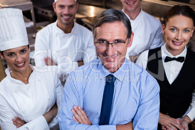 Happy restaurant team standing together with arms crossed in com