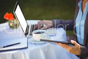 Businesswoman using tablet with coffee