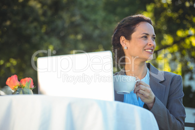 Businesswoman using laptop with coffee