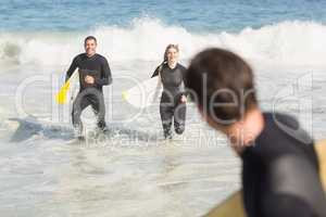 Couple with surfboard running on the beach