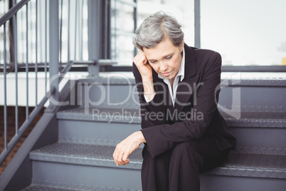 Upset businesswoman sitting on steps