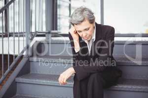 Upset businesswoman sitting on steps