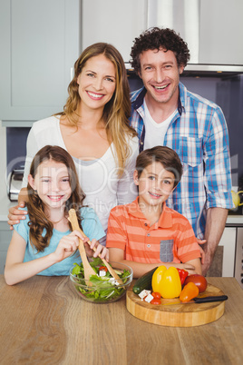 Portrait of happy family preparing vegetable salad