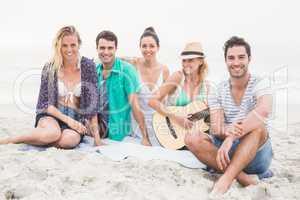 Group of friends sitting on the beach with guitar