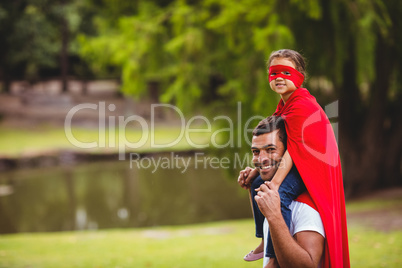 Girl in superhero costume sitting on fathers shoulder