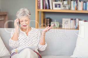 Senior woman talking on mobile phone while looking documents