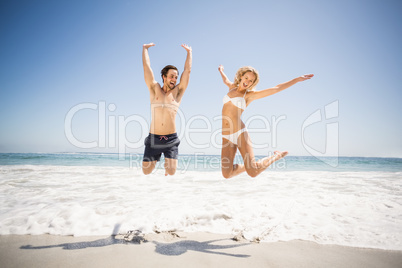 Happy couple jumping on the beach