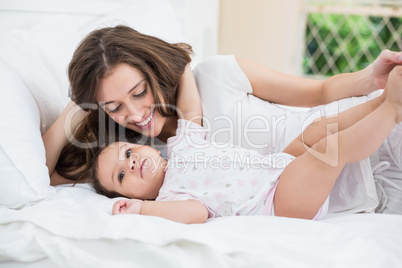 Mother lying with baby girl on bed