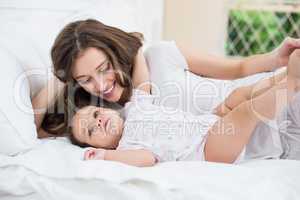 Mother lying with baby girl on bed